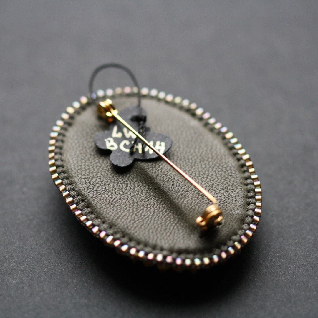 Embroidered brooch, rhyolite, green/bronze