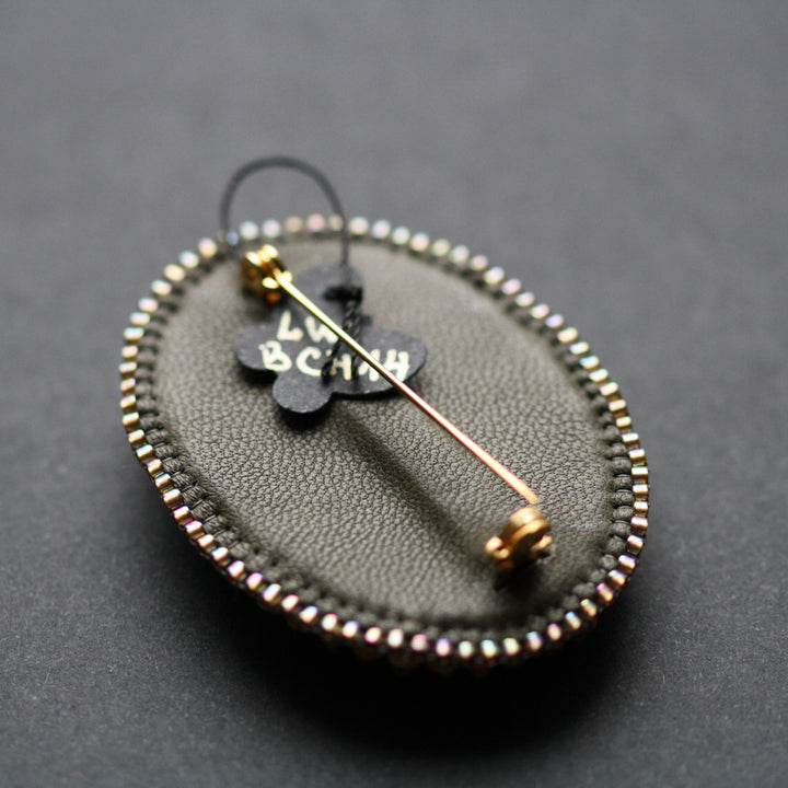 Embroidered brooch, rhyolite, green/bronze